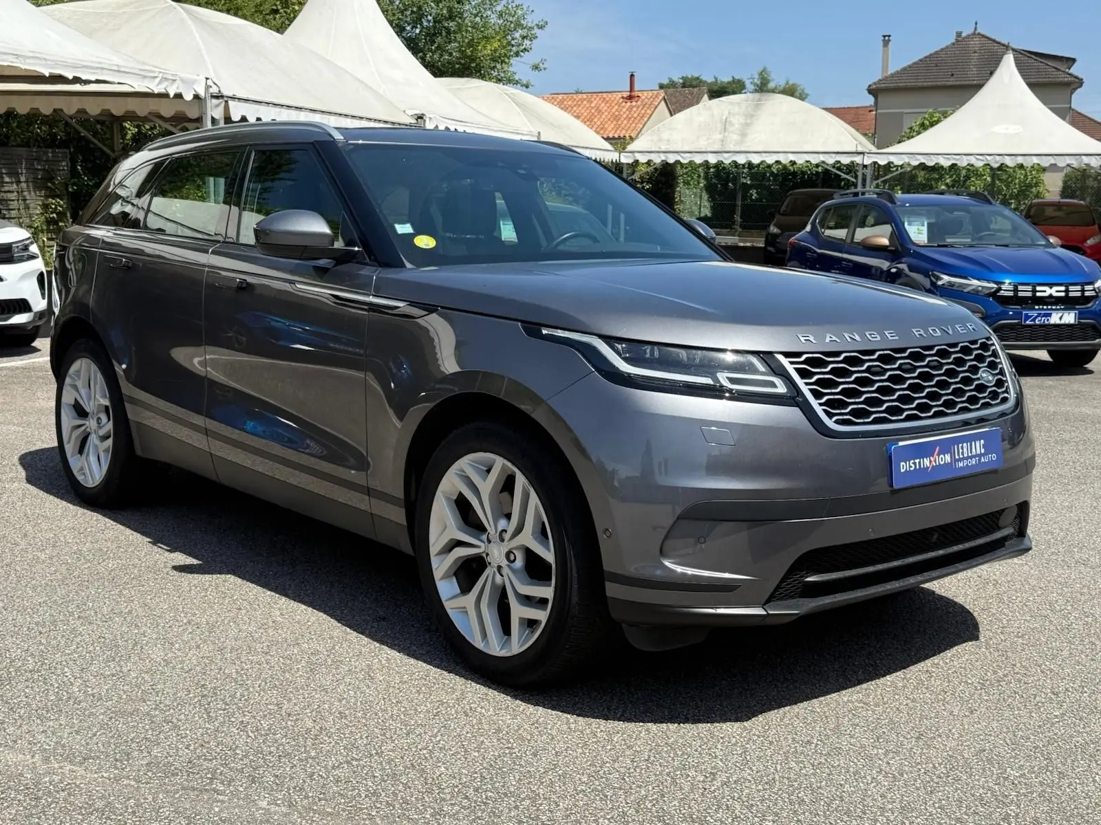 Range Rover Velar gris métallisé vu de trois quarts avant droit, avec calandre distinctive et jantes argentées.