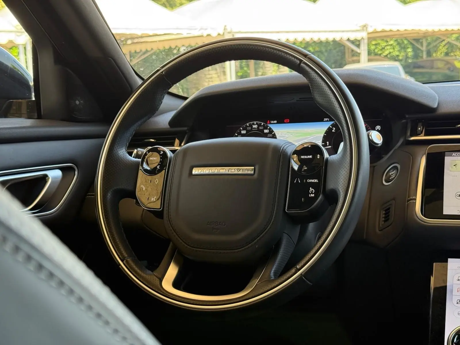 Vue intérieure centrée sur le volant cuir noir du Range Rover Velar 2019 avec tableau de bord numérique et écran tactile.