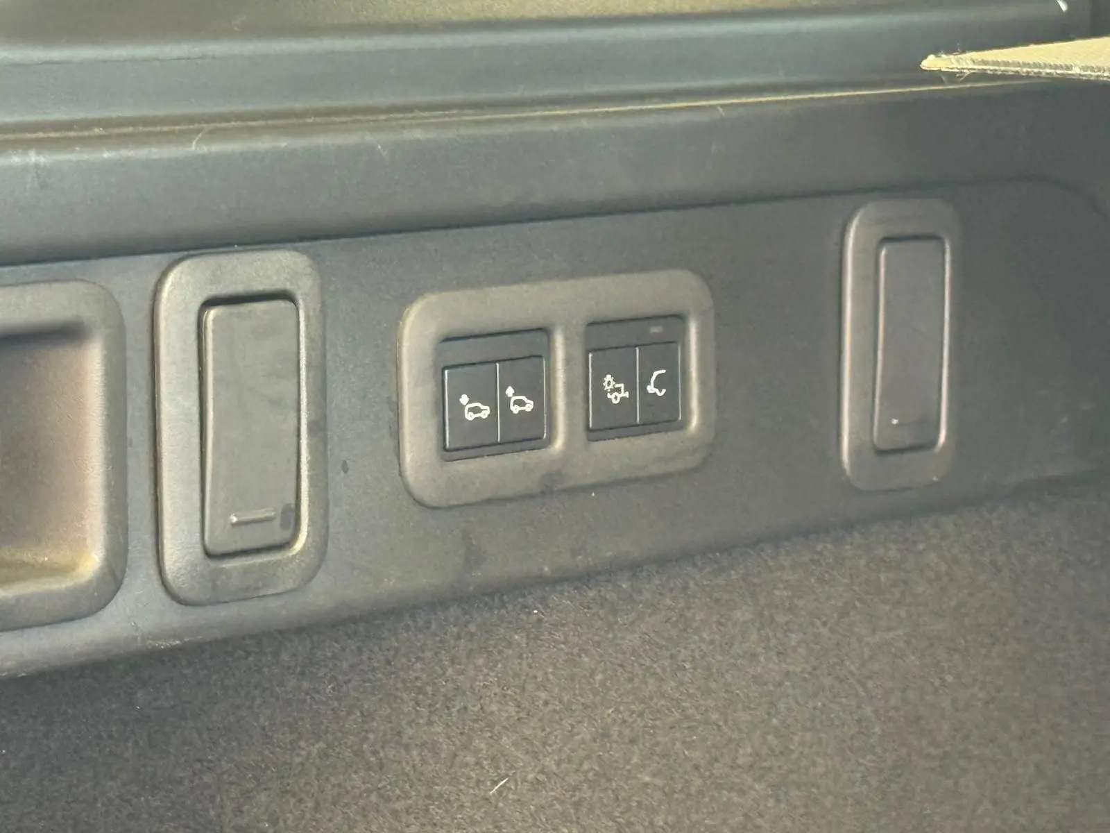 Gros plan sur les commandes du hayon électrique dans le coffre du Range Rover Velar gris 2019.