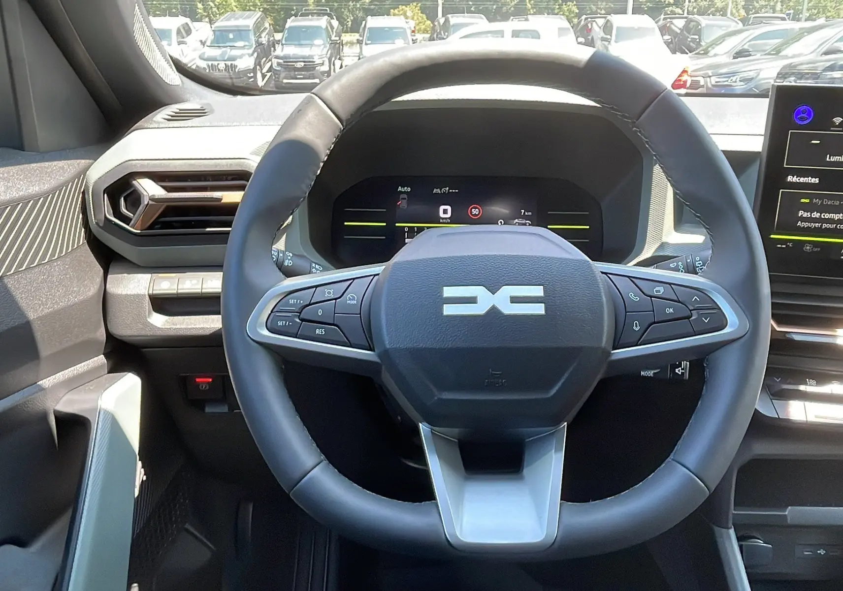 Vue intérieure centrée sur le volant multifonction du Dacia Duster 2025 avec tableau de bord numérique et écran tactile.