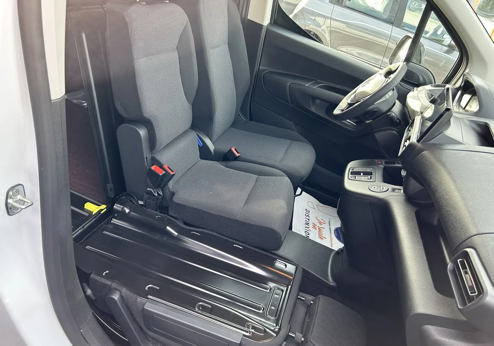 Vue intérieure côté conducteur du Peugeot Partner Fourgon blanc 2025, montrant les sièges tissu et le plancher bois noir.