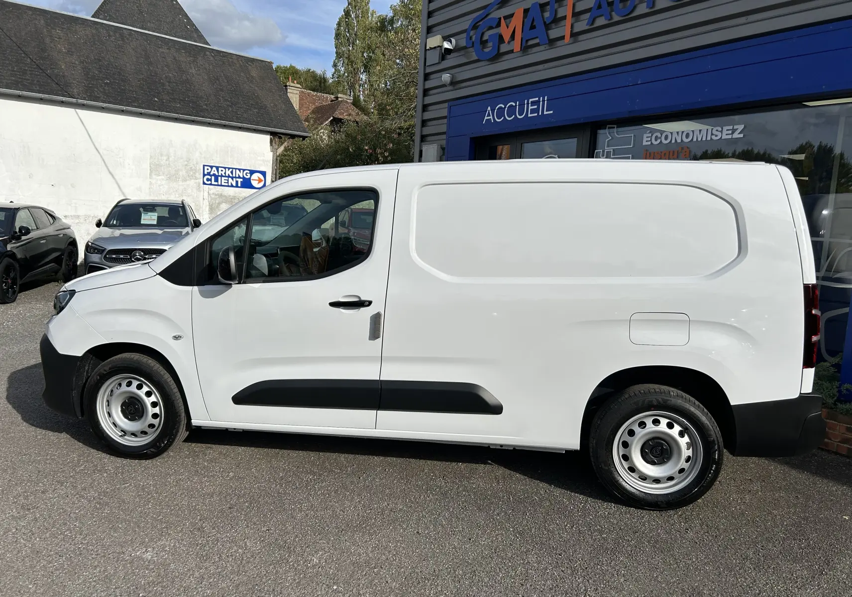 Peugeot Partner Fourgon blanc vu de profil côté gauche, avec protections latérales noires et jantes acier.