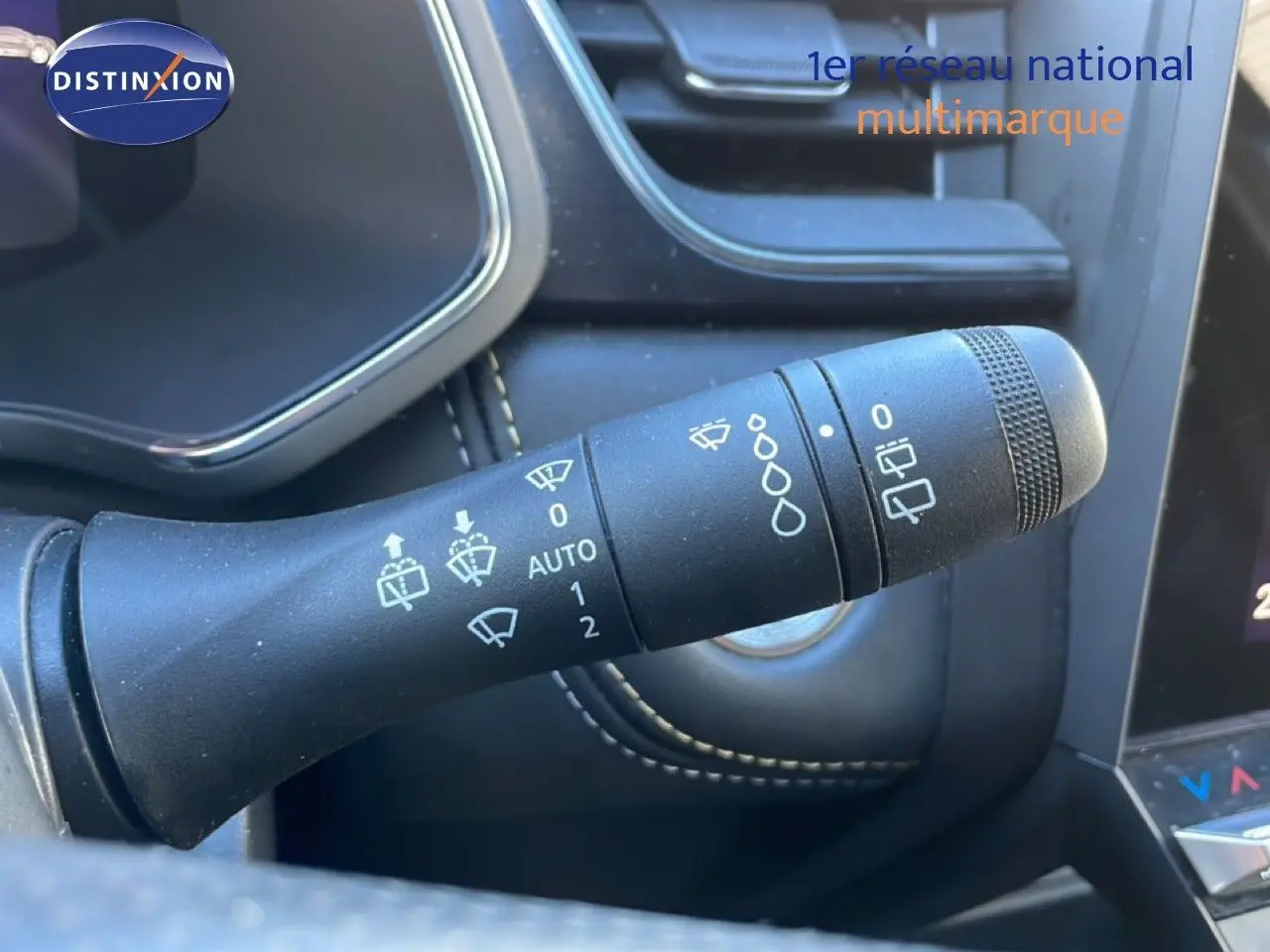 Gros plan sur la commande d’essuie-glace noire dans l’habitacle du Renault Symbioz bleu iron metal, avec coutures blanches visibles.