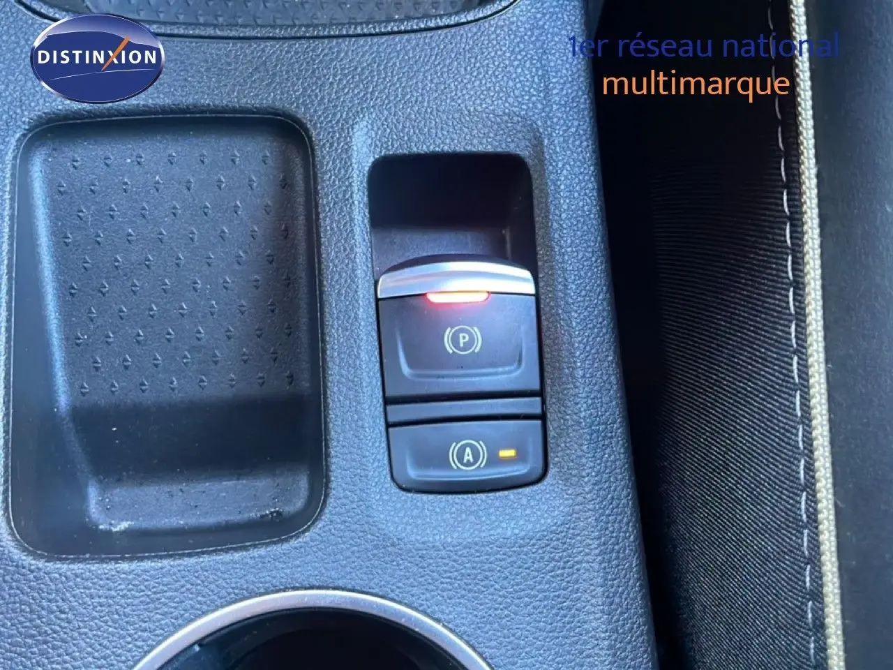 Gros plan sur la console centrale noire du Renault Symbioz 2025 avec boutons de frein à main et démarrage automatique éclairés.