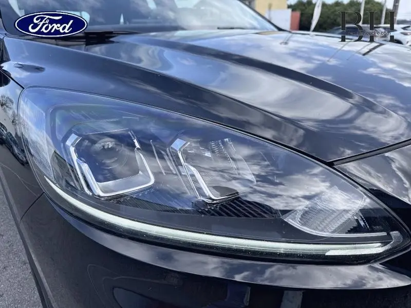 Gros plan sur le phare avant gauche du Ford Kuga noir Agate Métallisée, mettant en valeur ses lignes LED modernes.