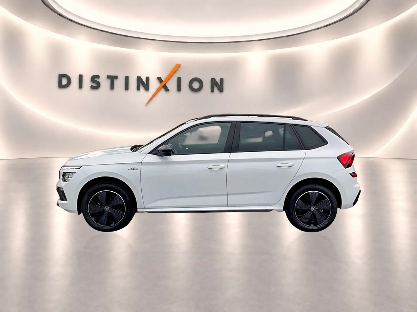 Profil droit du Skoda Kamiq blanc nacré avec jantes noires et toit panoramique en arrière-plan lumineux.