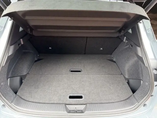 Coffre ouvert du Nissan Qashqai gris foncé 2025, montrant l'espace de chargement avec hayon électrique relevé.