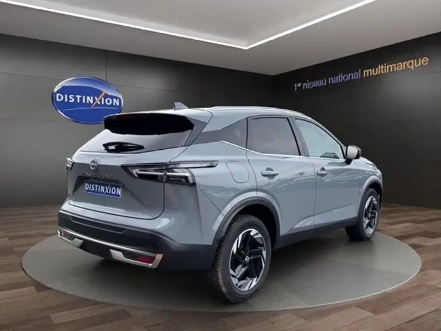 Vue 3/4 arrière droite du Nissan Qashqai gris foncé 2025 avec hayon électrique dans un showroom.