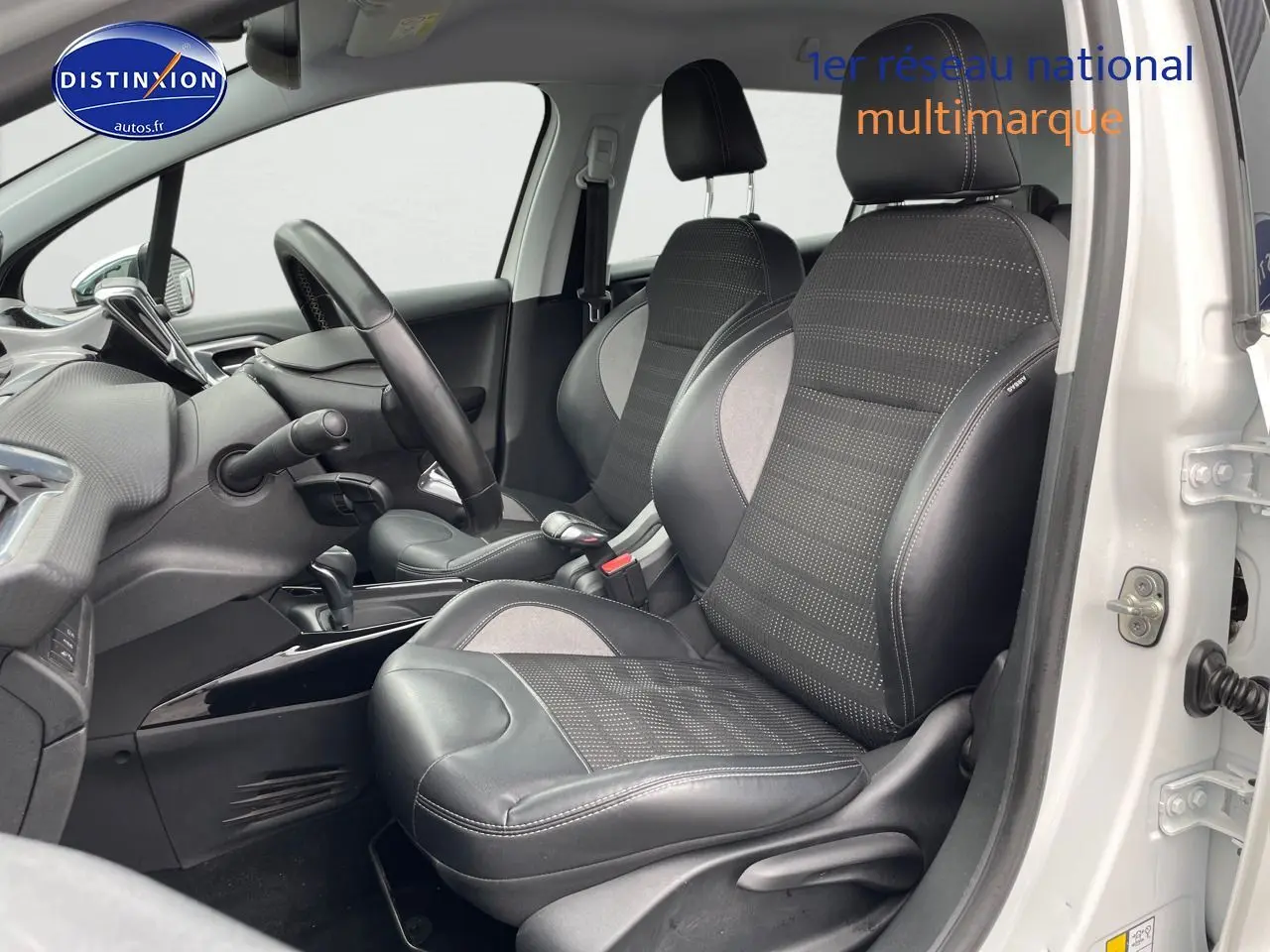 Vue intérieure côté conducteur d'une Peugeot 2008 blanc nacré, sièges en cuir noir avec surpiqûres blanches.