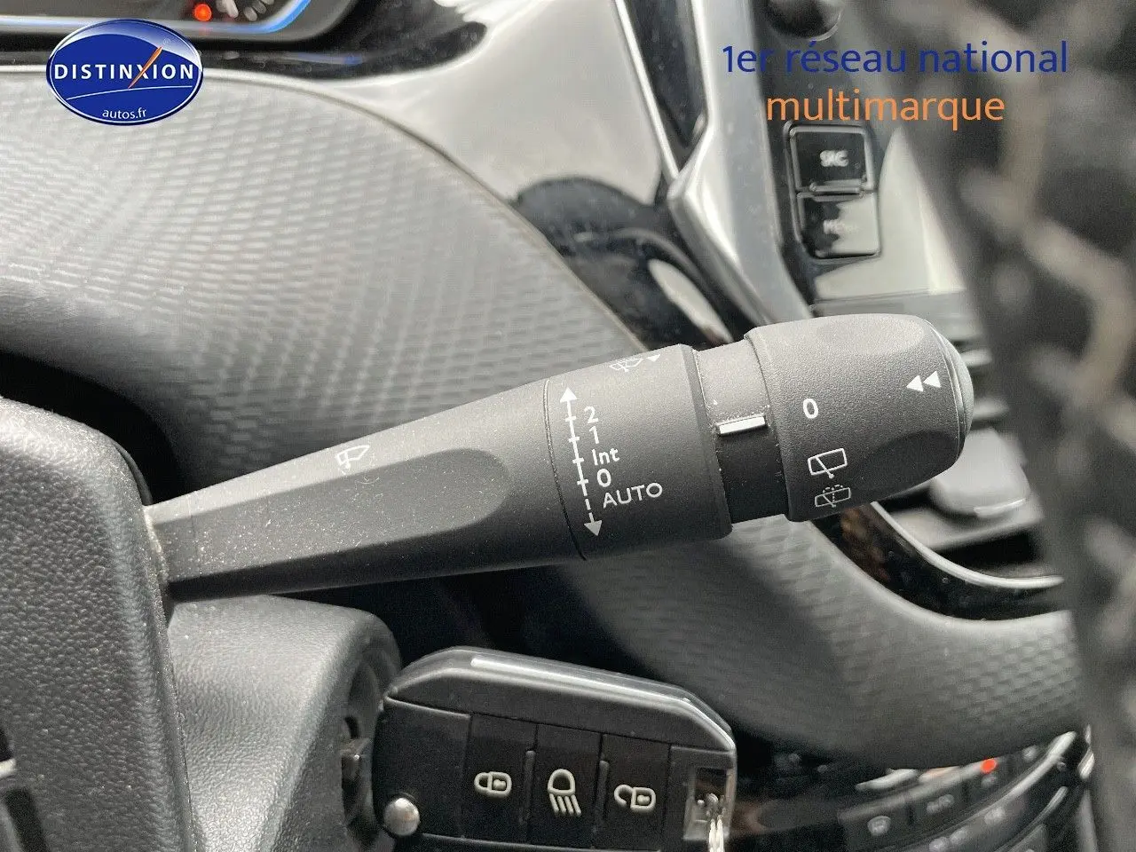 Gros plan sur la commande d'essuie-glace à gauche du volant dans l'habitacle d'un Peugeot 2008 blanc nacré de 2015.