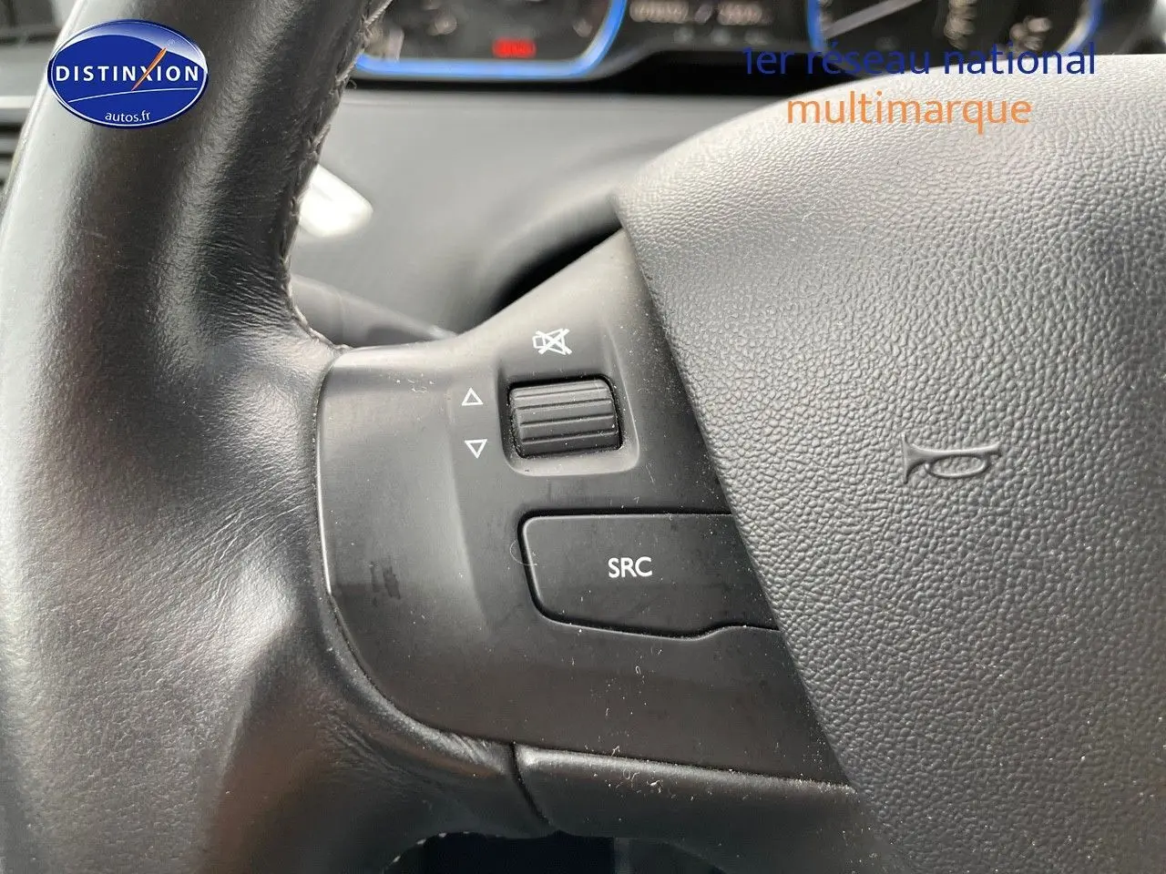 Gros plan sur les commandes audio au volant noir du Peugeot 2008 blanc nacré, version essence 2015.