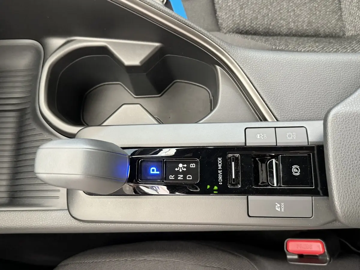 Vue rapprochée de la console centrale du Toyota C-HR blanc 2024, avec levier de vitesse automatique et boutons de mode de conduite.