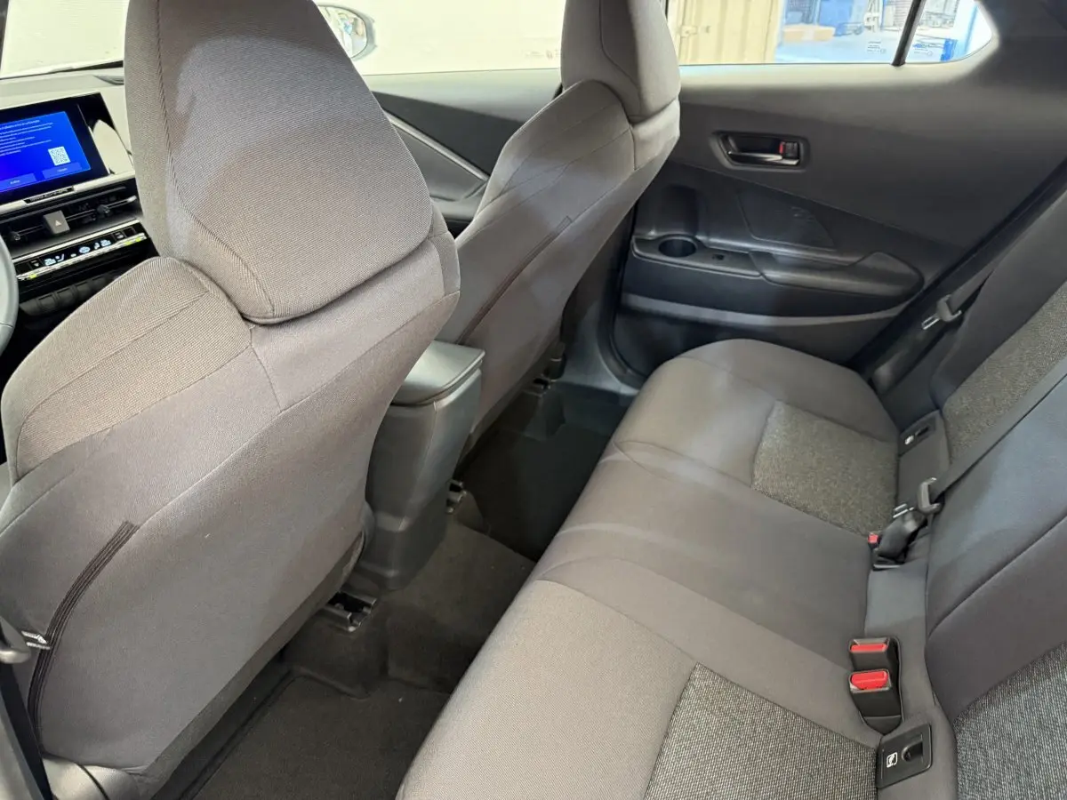 Vue intérieure arrière côté droit du Toyota C-HR blanc 2024, sièges tissu gris et console centrale visible.