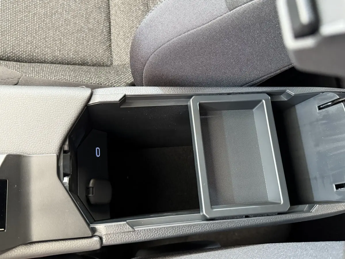 Vue rapprochée de l'accoudoir central ouvert du Toyota C-HR blanc 2024, montrant le rangement intérieur noir.