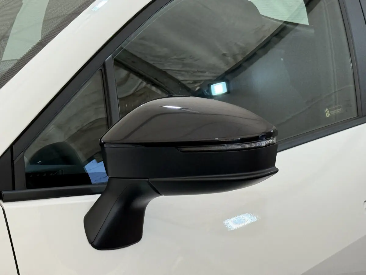 Rétroviseur côté gauche noir brillant du Toyota C-HR 1.8 Hybride blanc, avec clignotant intégré, vue rapprochée.