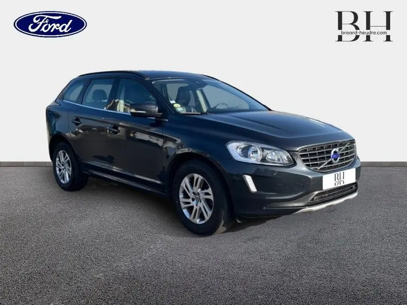 SUV Volvo XC60 gris foncé en vue 3/4 avant droit, avec jantes alliage et calandre distinctive visible.