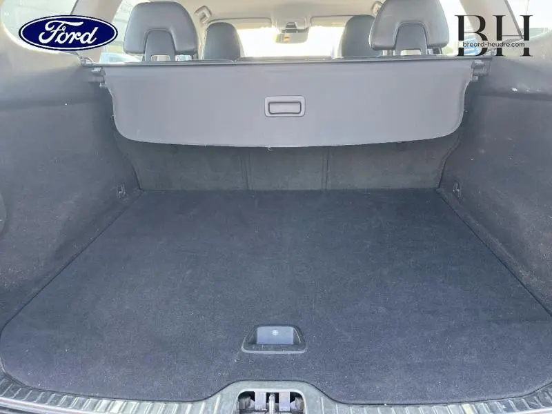 Vue du coffre arrière spacieux et propre du Volvo XC60 D3 150ch Momentum Business gris Savile, avec cache-bagages déployé.