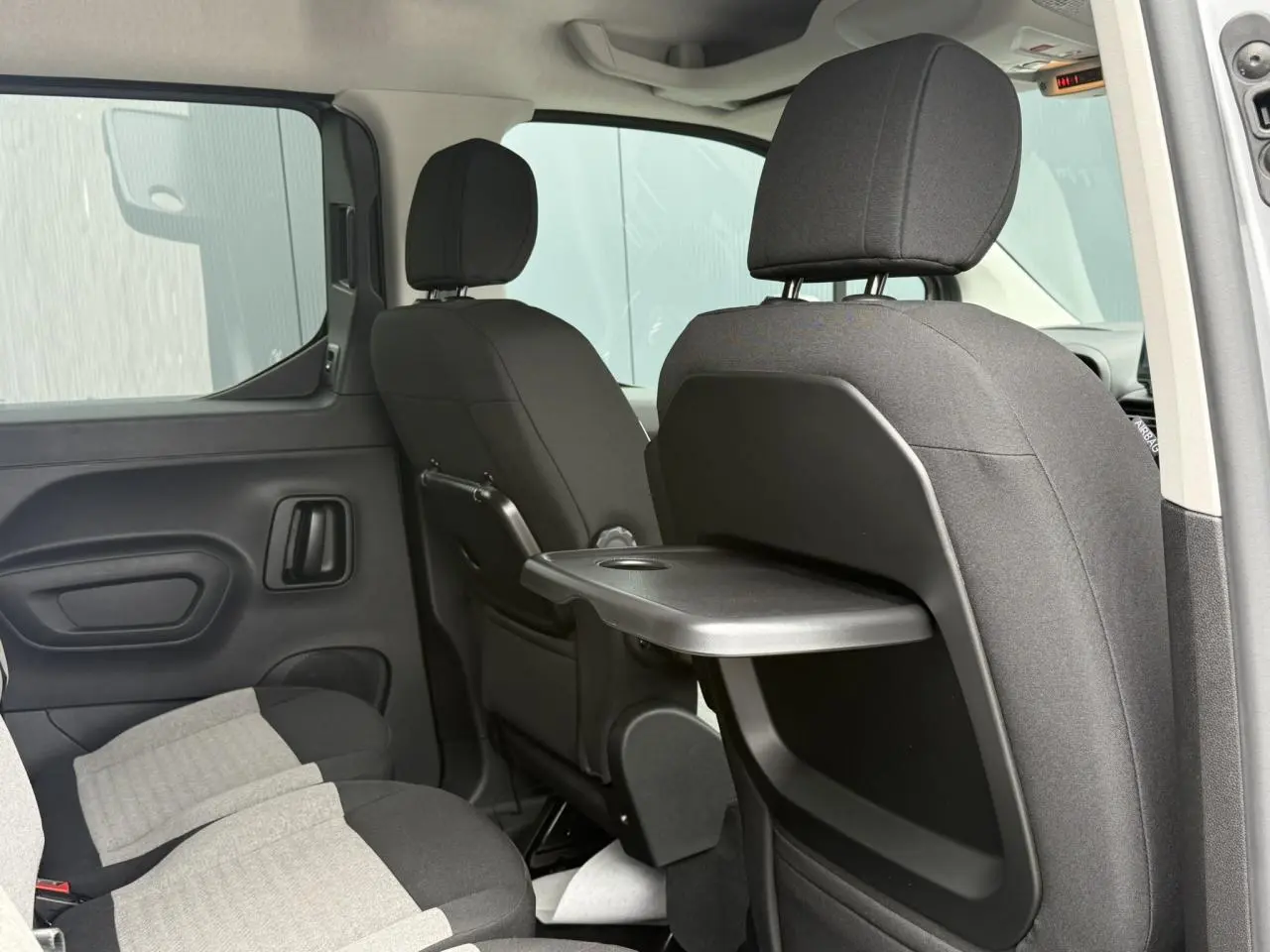 Vue intérieure côté droit des sièges arrière gris foncé et clair du Citroën Berlingo Multispace 2026 avec tablette escamotable.