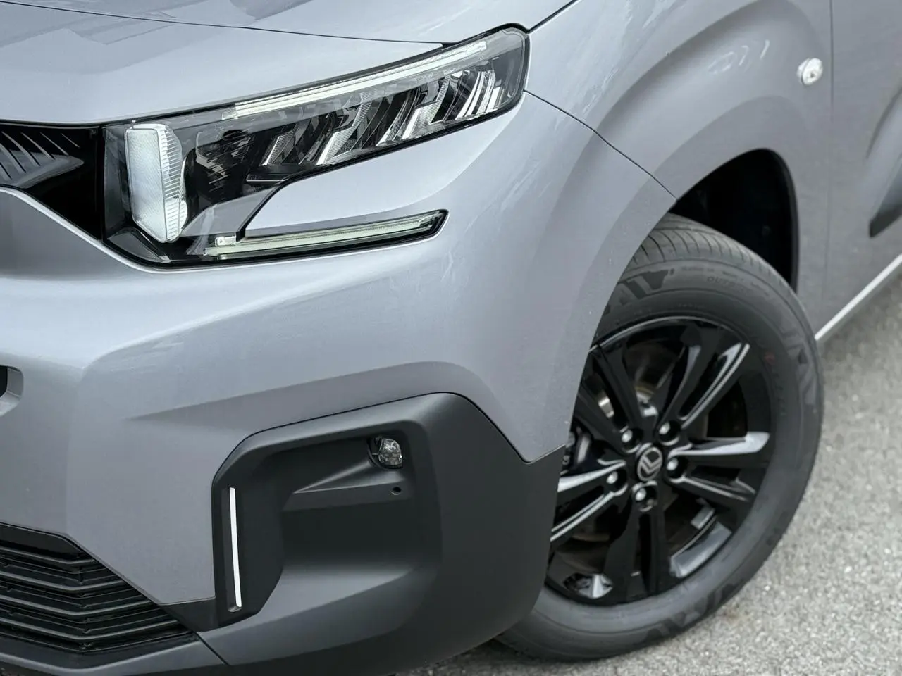 Gros plan sur l'avant droit gris acier du Citroën Berlingo Multispace 2026 avec jante alliage noire et phare LED.