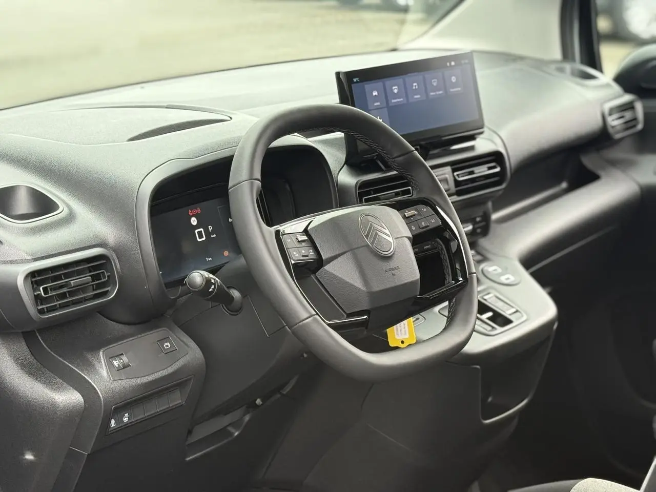 Vue intérieure du poste de conduite du Citroën Berlingo Multispace gris, avec volant multifonctions et écran tactile central.