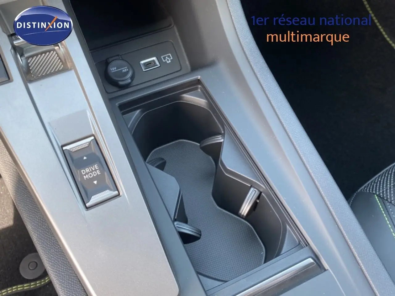Gros plan sur la console centrale noire avec porte-gobelets et bouton Drive Mode de la Peugeot 308 hybride 2026.