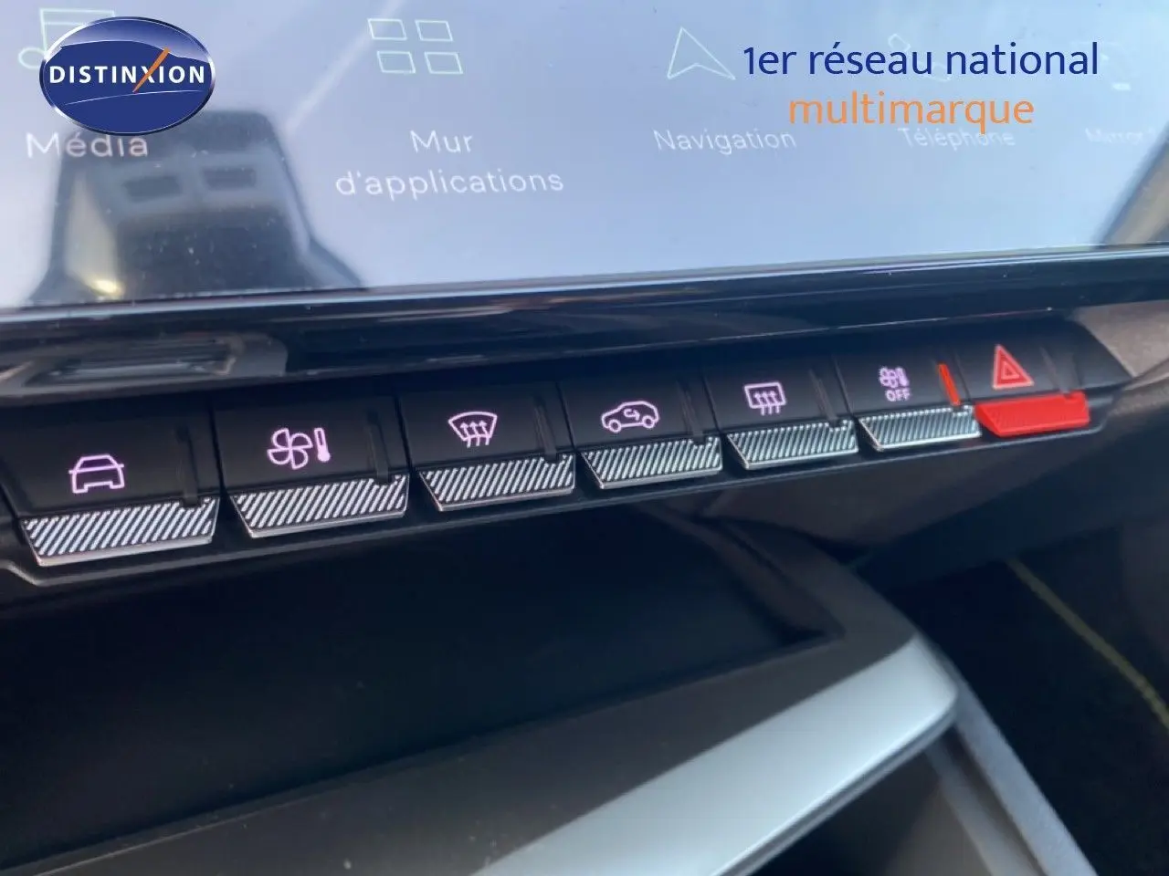 Vue rapprochée des commandes tactiles de la console centrale du Peugeot 308 blanc Okenite, avec boutons rétroéclairés et alerte rouge.