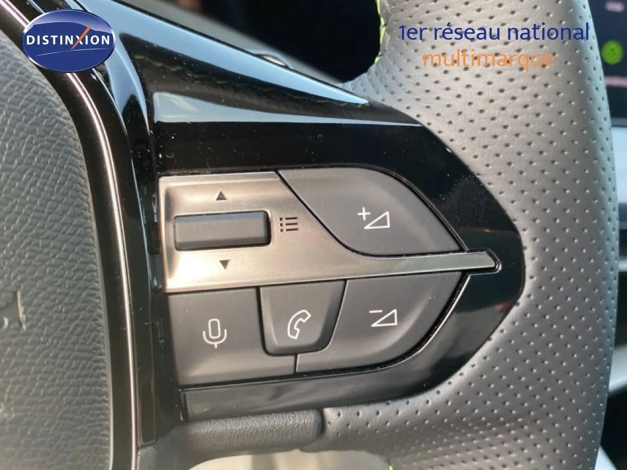 Gros plan sur les commandes noires du volant perforé d’une Peugeot 308 hybride blanche, avec boutons de volume et appel.