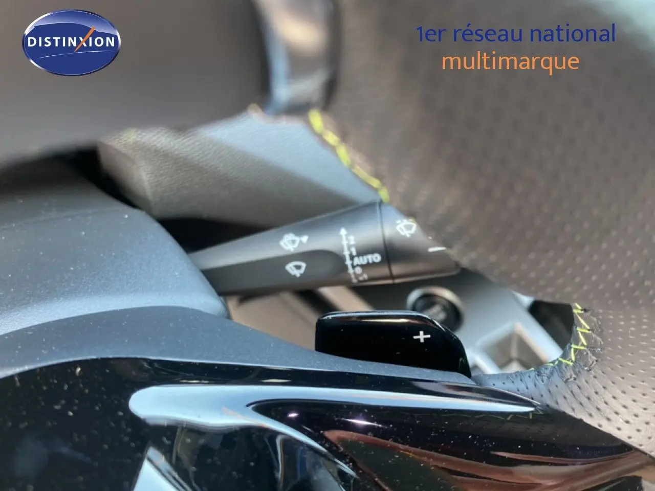 Gros plan sur la palette de changement de vitesse au volant perforé avec surpiqûres jaunes d'une Peugeot 308 blanche.