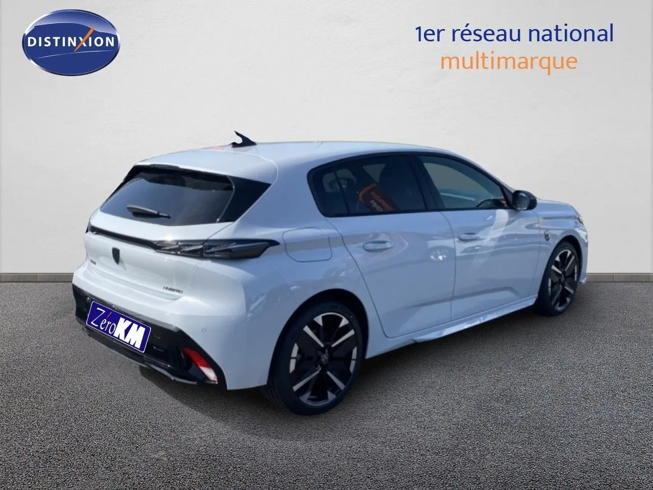 Vue 3/4 arrière droite d'une Peugeot 308 blanche Okenite Hybrid 2026 avec jantes noires et vitres teintées.