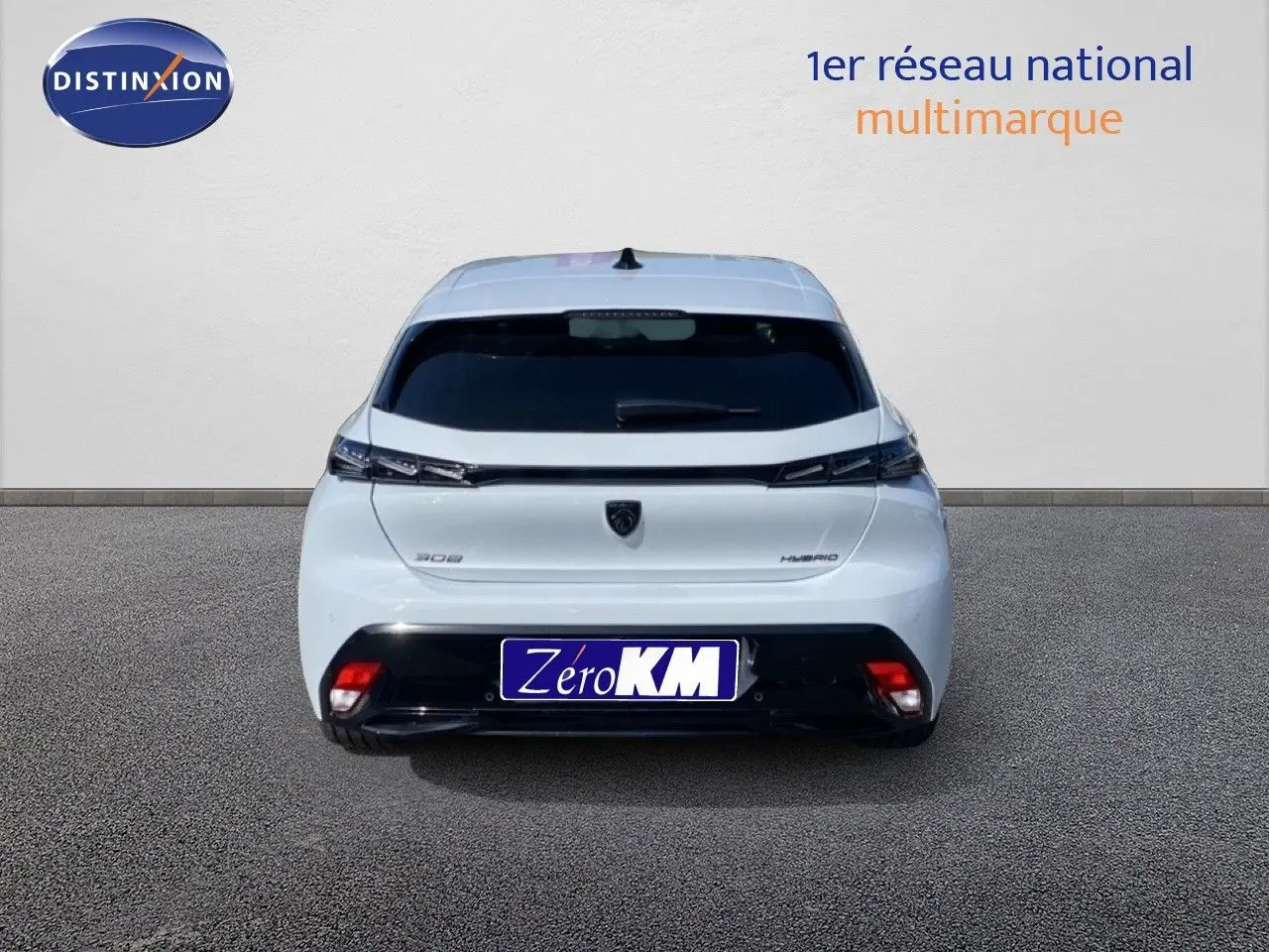 Vue arrière d'une Peugeot 308 blanche Okenite Metal, avec feux arrière fins et logo central visible.