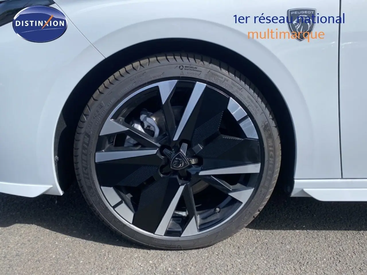 Gros plan sur la roue avant droite noire et argentée d’une Peugeot 308 blanche Okenite Metal de 2026.