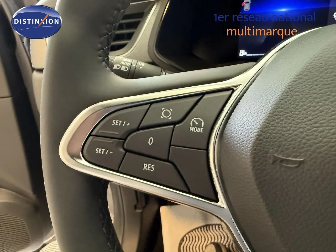 Gros plan sur les commandes au volant du Renault Captur gris Cassiopée, mettant en valeur les boutons de régulateur de vitesse.