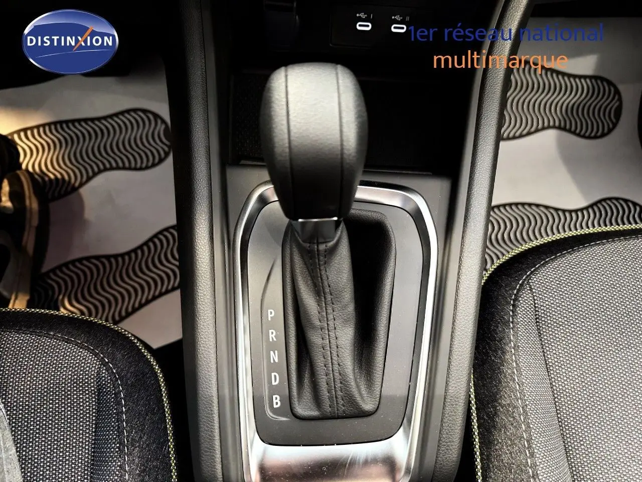 Le levier de vitesses automatique noir du Renault Captur 1.6 E-TECH Full Hybrid, vu de dessus, entouré de sièges gris.