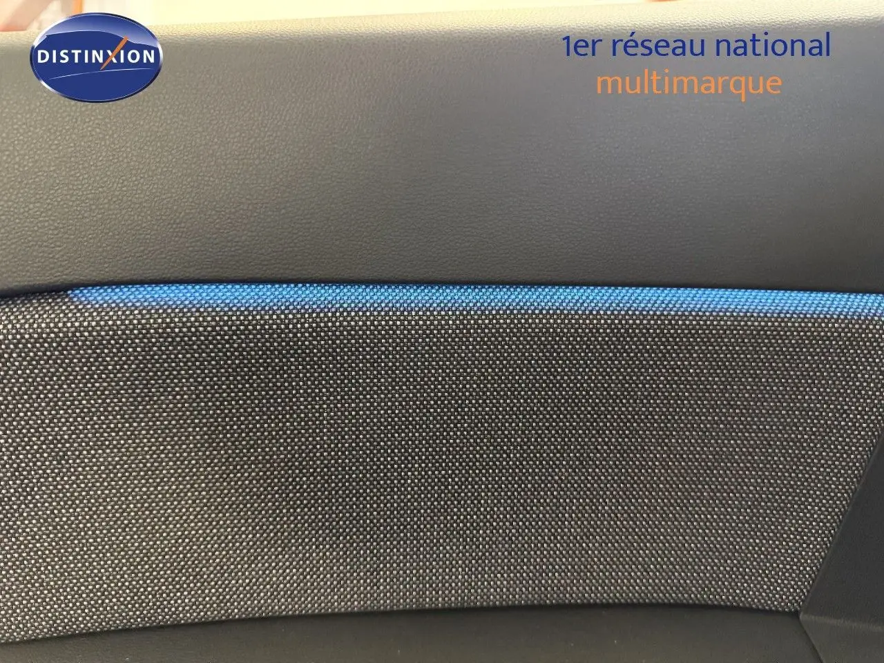 Détail intérieur montrant la texture grise et la bande bleue du tissu sur la porte d’un Renault Captur 2025 hybride.