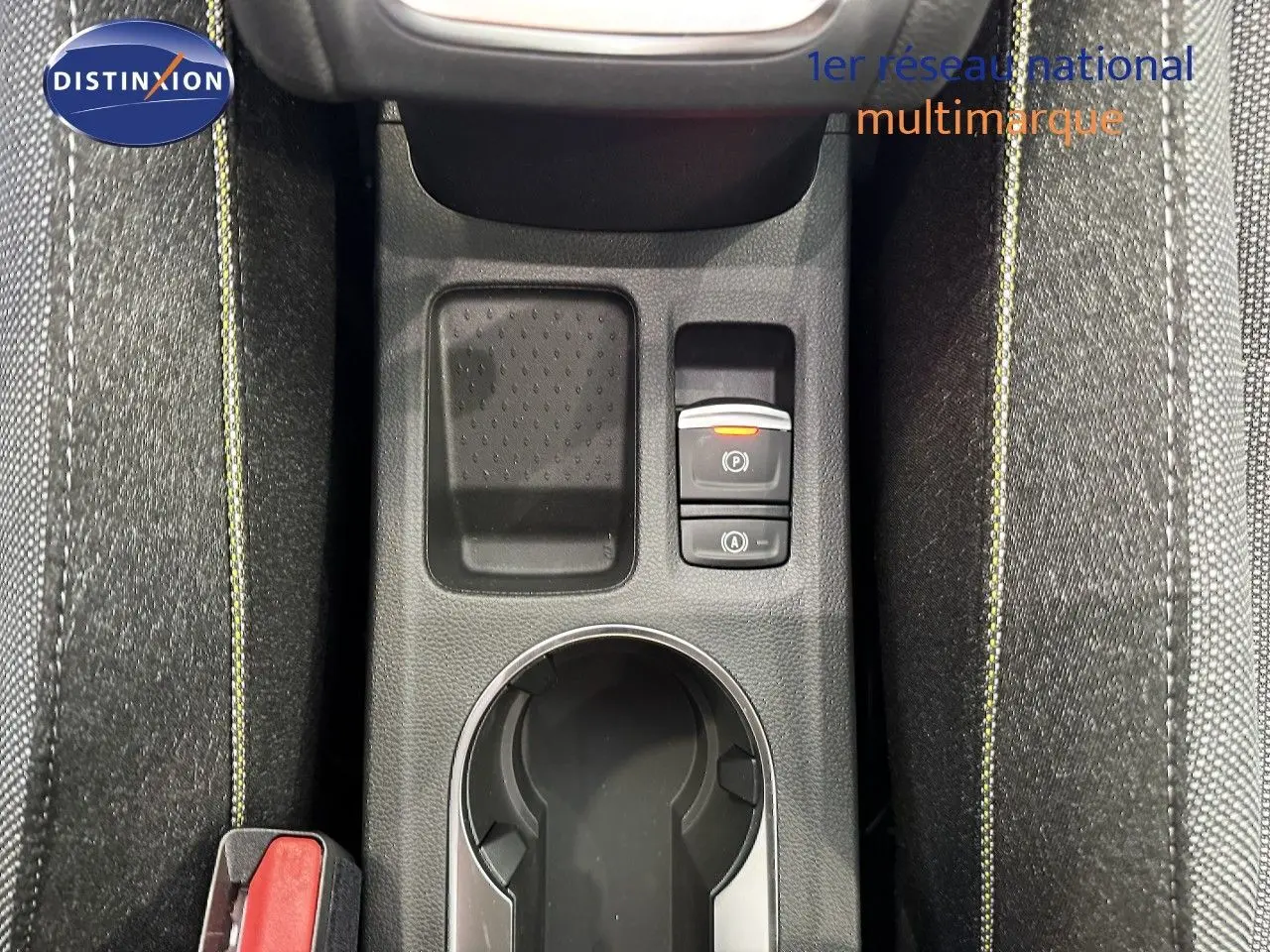 Vue plongeante sur la console centrale du Renault Captur gris Cassiopée, avec bouton frein à main électronique et surpiqûres jaunes.