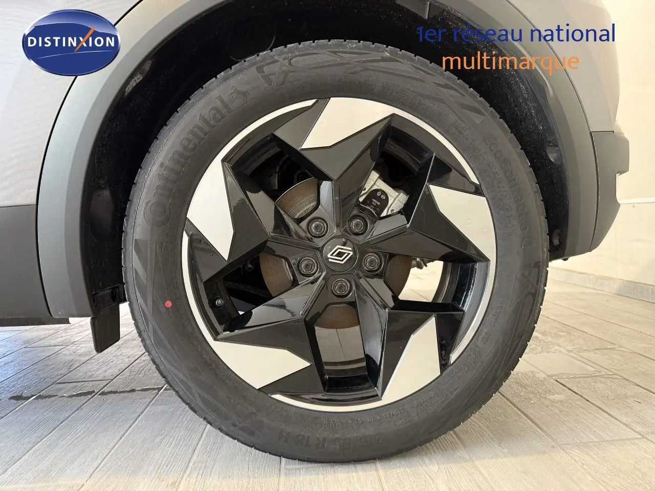 Gros plan sur la roue avant droite du Renault Captur gris Cassiopée Métal avec jante noire et argentée au design étoilé.