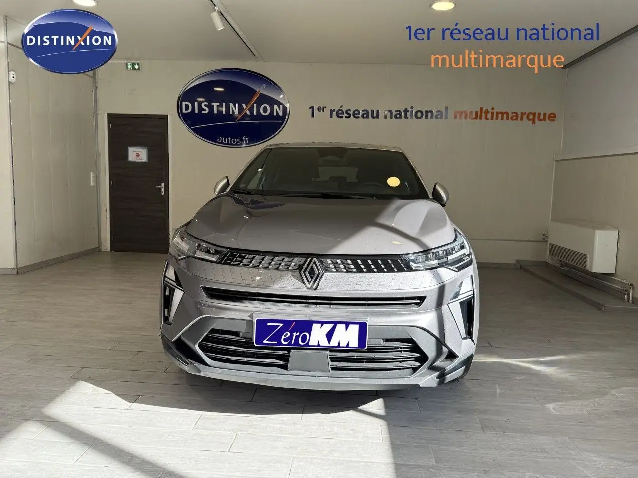 Vue frontale d'un Renault Captur 2025 gris Cassiopée métal avec toit gris, dans un showroom lumineux.