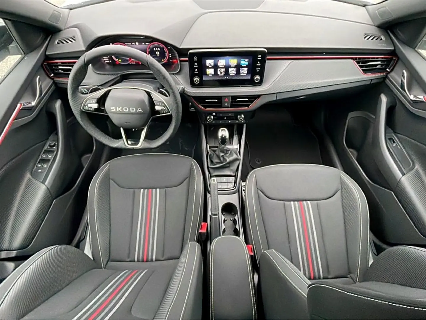 Vue intérieure frontale du Skoda Kamiq Monte Carlo 2026, sièges noirs avec bandes rouges et tableau de bord moderne.