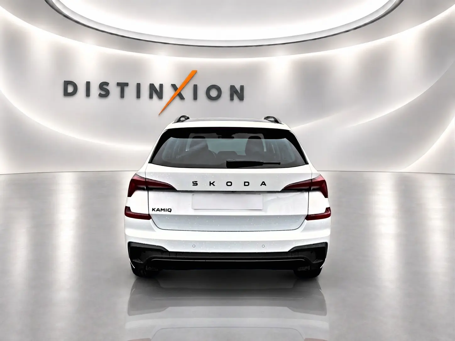 Vue arrière d’un Skoda Kamiq blanc nacré avec feux arrière LED et diffuseur noir dans un showroom lumineux.