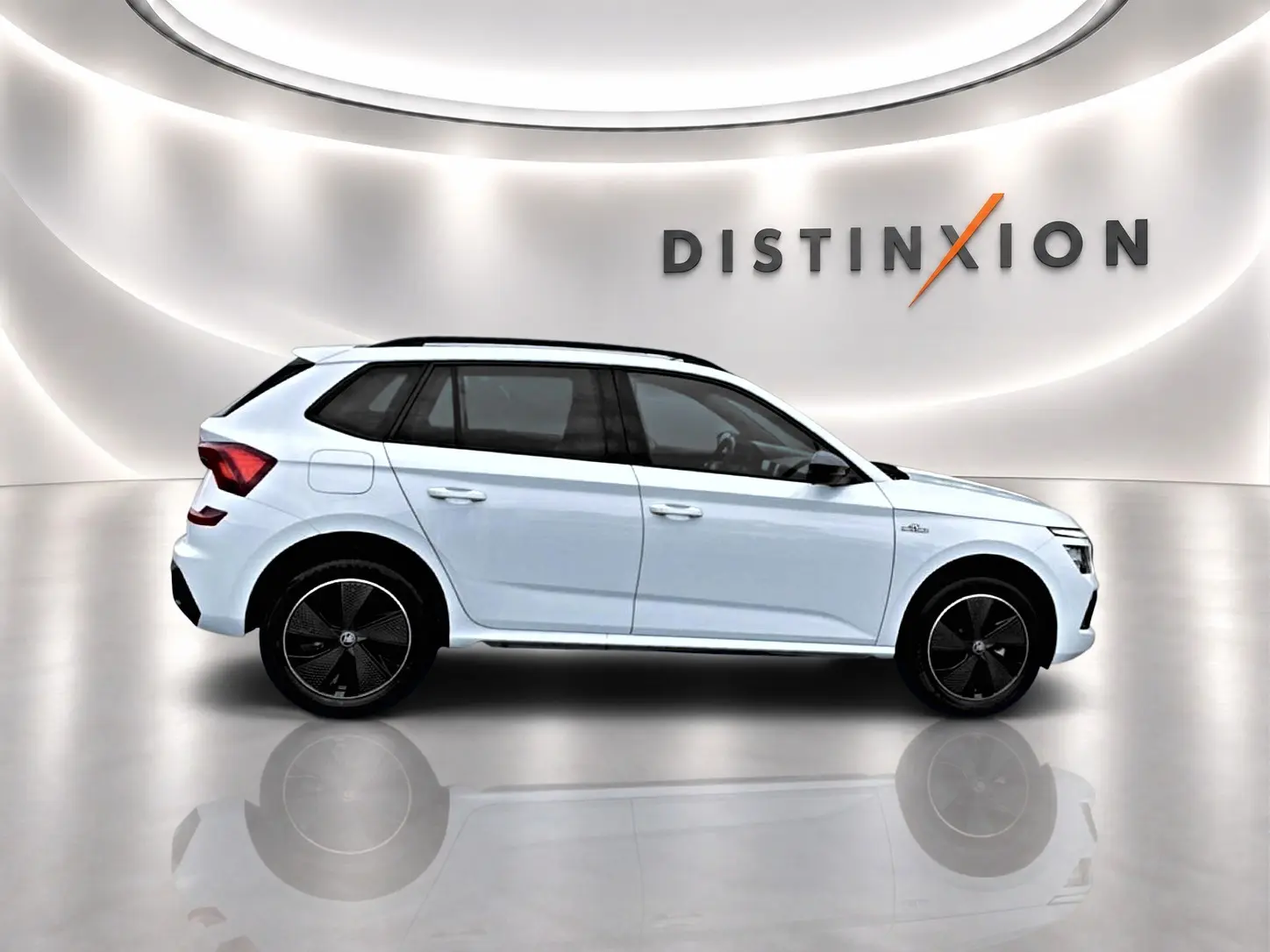 Vue de profil côté gauche d'un Skoda Kamiq blanc nacré avec jantes noires et toit panoramique en studio lumineux.