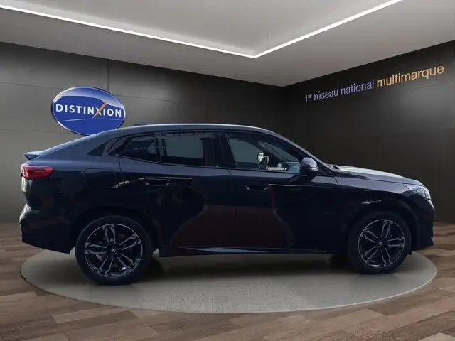 Profil droit d’un BMW X2 noir 2025 en finition M Sport, avec jantes alliage et toit incliné dans un showroom.