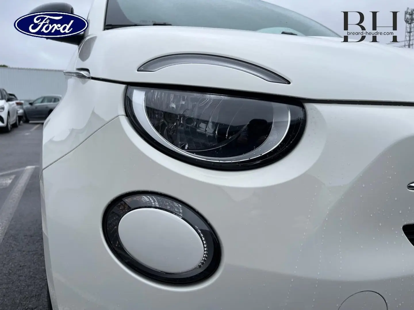Gros plan sur l'avant gauche de la FIAT 500 Ice White pastel, mettant en valeur son phare rond et son antibrouillard.