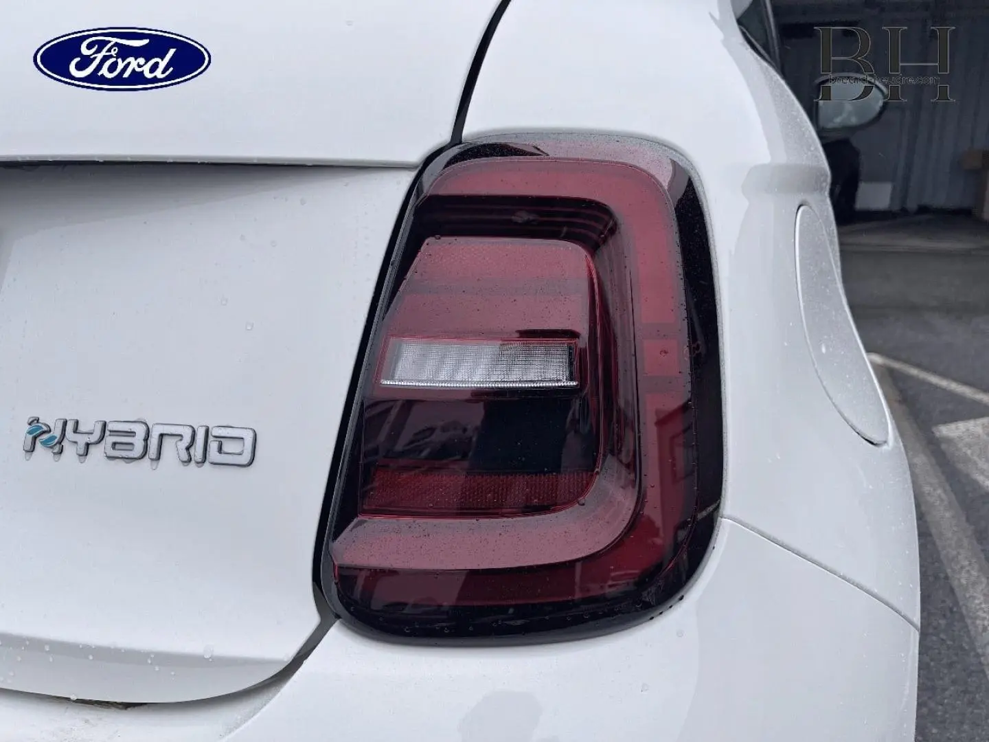 Gros plan sur le feu arrière droit d'une FIAT 500 Ice White pastel avec logo Hybrid sur fond blanc.