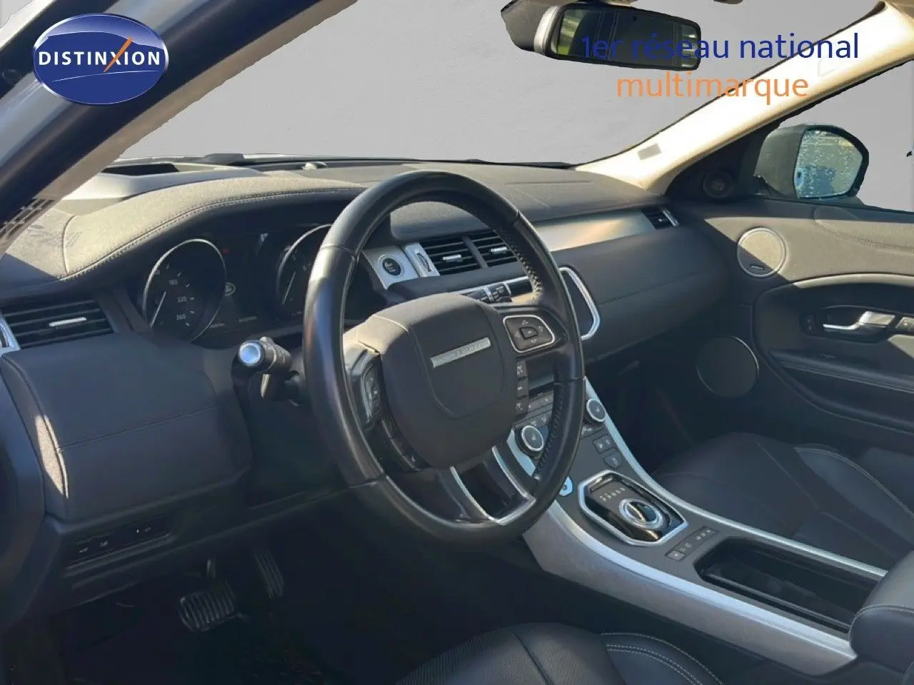 Intérieur noir du Range Rover Evoque 2017 vu côté conducteur, avec tableau de bord moderne et volant multifonction.