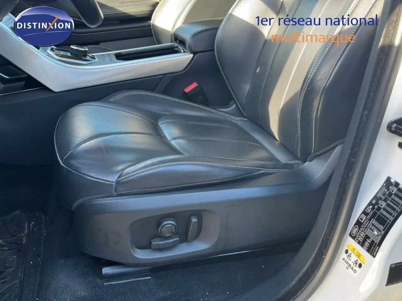 Gros plan sur le siège conducteur en cuir noir du Range Rover Evoque blanc, avec commandes électriques visibles sur le côté.