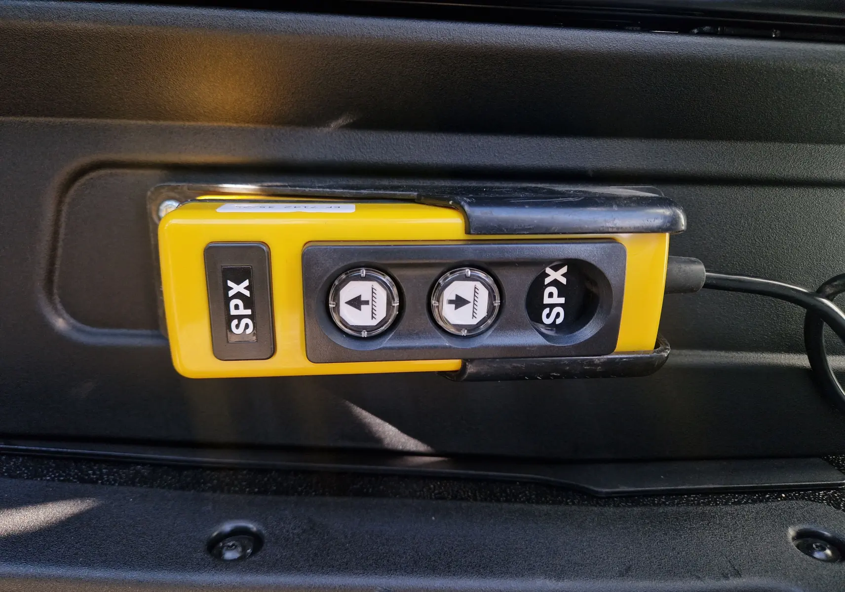 Télécommande jaune SPX avec deux boutons fléchés, fixée à l'intérieur d'un Iveco Daily Chassis Cabine blanc.