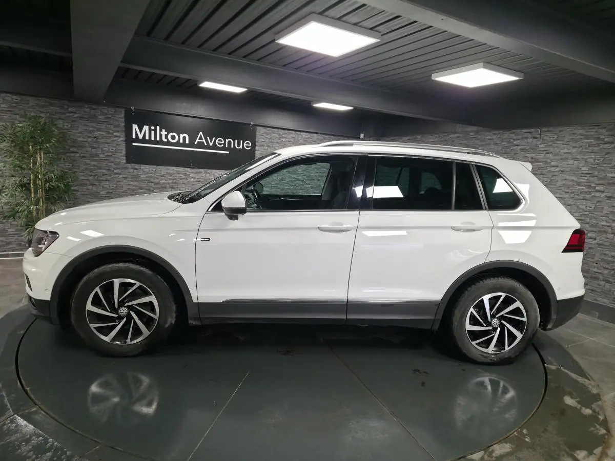 Volkswagen Tiguan blanc vu de profil côté gauche, avec jantes alliage 17 pouces et barres de toit.