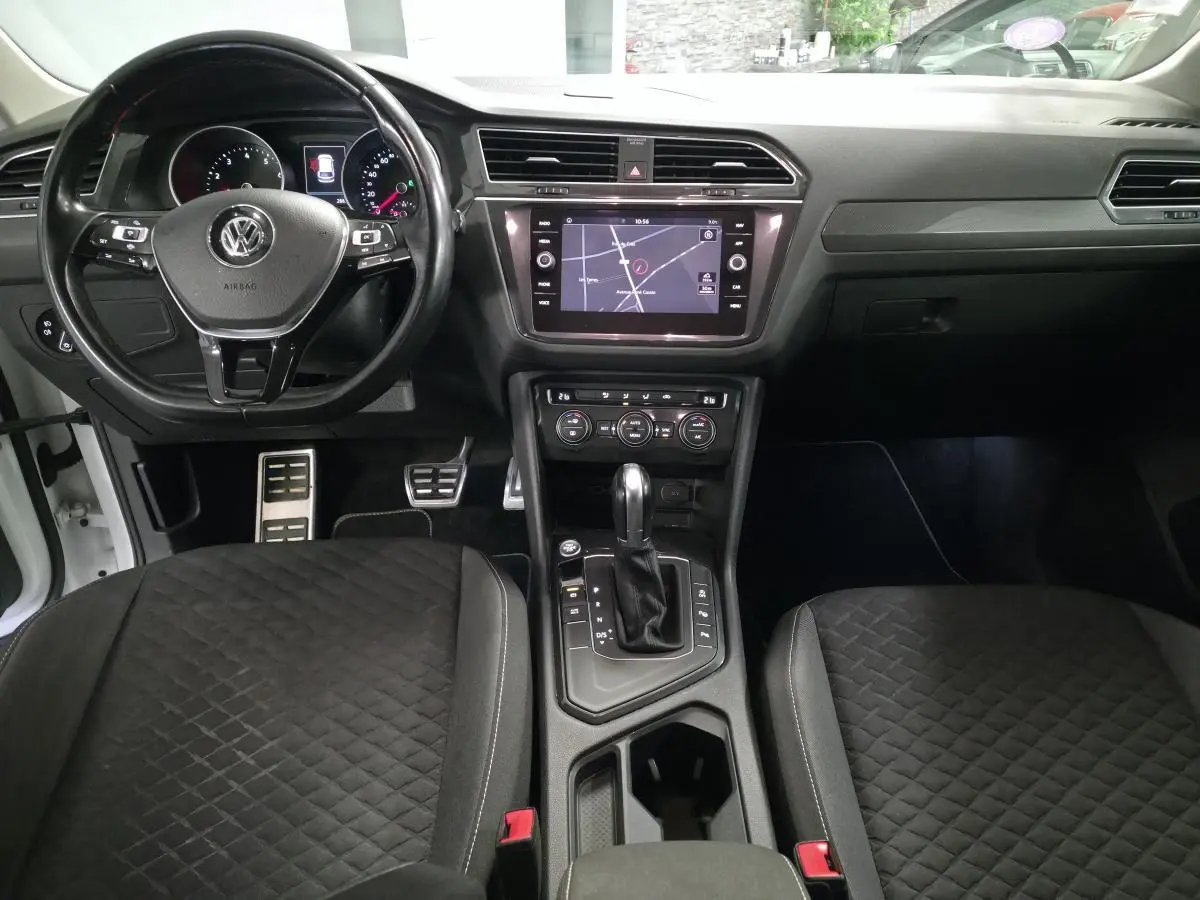 Vue intérieure avant du Volkswagen Tiguan 2019 blanc, tableau de bord avec écran tactile et volant multifonction cuir.