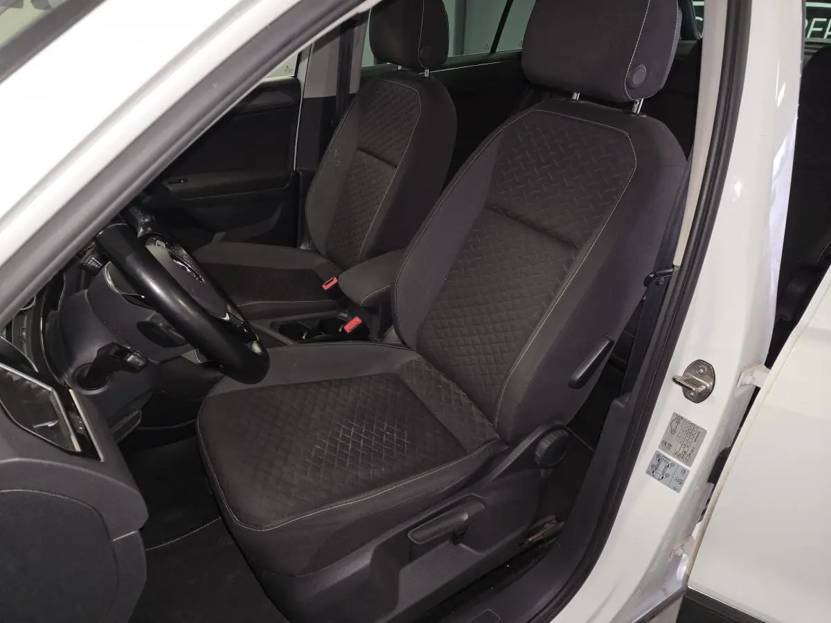 Vue intérieure côté conducteur du Volkswagen Tiguan blanc, sièges tissu noir à motif losanges.