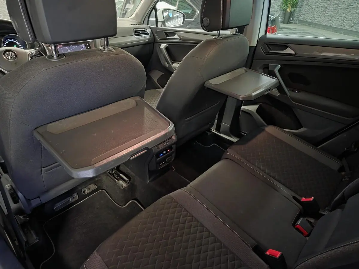 Vue intérieure arrière du Volkswagen Tiguan 2019 avec tablettes rabattables sur les dossiers des sièges avant et sellerie tissu noire.